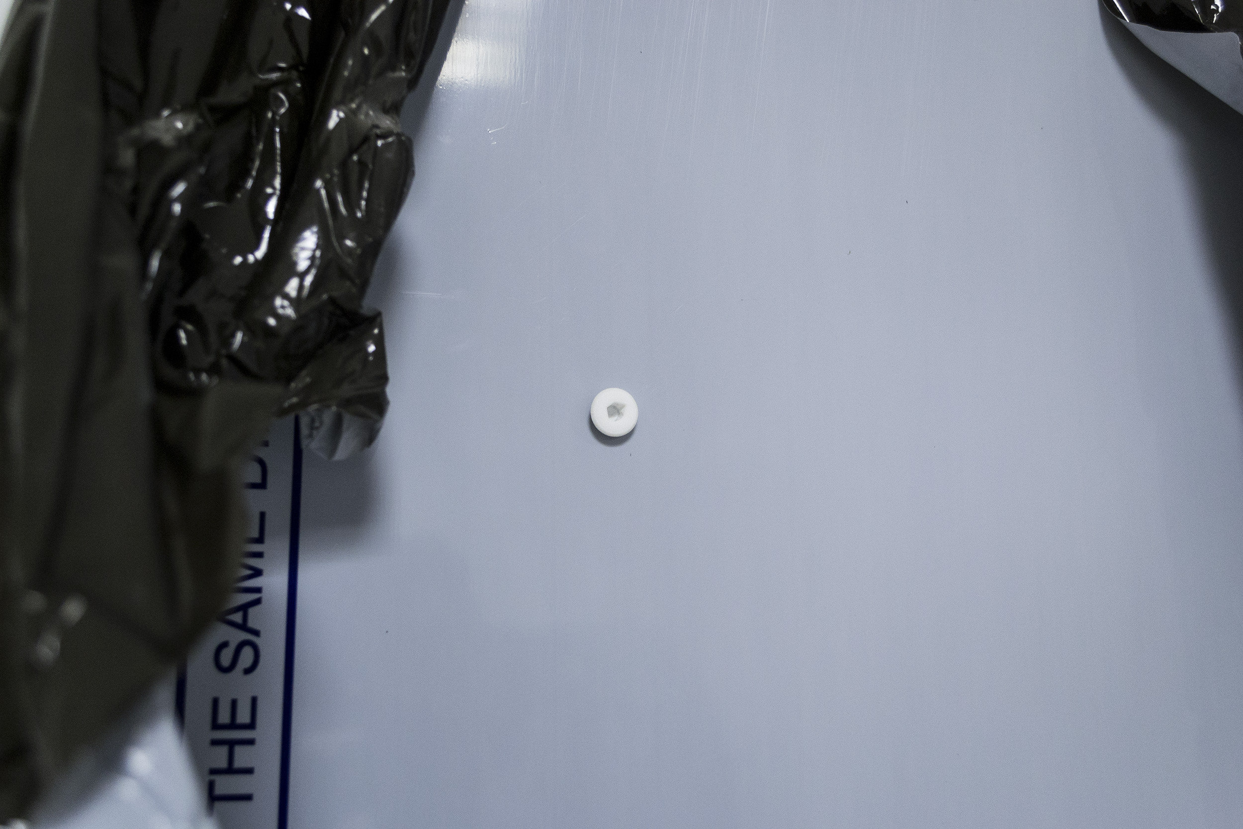 Retained Obstruction No.2, 2014 125 x 125 cm Dibond, Pulled off plastic protector, 3 M6 Allen screws, 1 3D printed and modified M6 Allen screw, remains of wall 